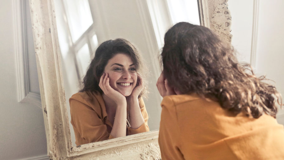 woman mirror thinking about Dental Implants and Dentures