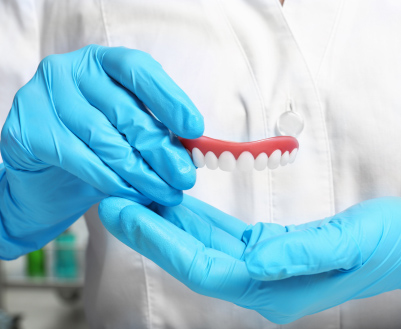 Dentist in Norwalk, IA specializing in restorative dentistry holding dentures